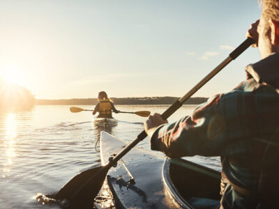 Two people kayaking on a calm lake at sunset